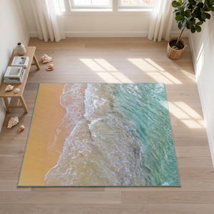 Könnte beinhalten: Ein rechteckiger Teppich mit einem hochauflösenden Fotodruck eines sandigen Küstenabschnitts. Das Design zeigt goldgelben Sand, der auf weißen Meeresschaum und türkisfarbenes Ozeanwasser trifft und so eine realistische Küstenszene erzeugt.