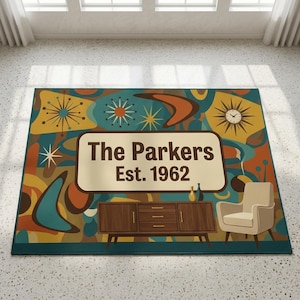 May include: A rectangular area rug featuring a colourful mid-century pattern with starbursts, boomerangs, and a clock. A central cream-coloured rectangle displays the text The Parkers Est. 1962. Below, a wooden sideboard and a cream armchair are depicted.