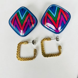 May include: A pair of earrings with a geometric design. The earrings are made of blue and red plastic with a gold metal hoop.