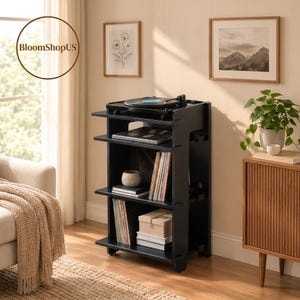 May include: A black wooden record player stand with four tiers. The top surface holds a turntable, while the lower shelves store vinyl records, a small bowl, and boxes. The stand features a vertical design with open sides and a smooth finish.