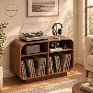 May include: A mid-century modern walnut wood record player console with rounded edges. The top holds a silver turntable and a headphone stand with black headphones. The shelves contain a speaker, a flip clock, and vinyl records.