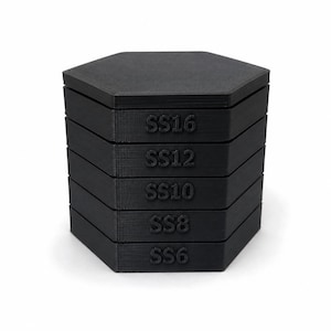 May include: A stack of five black hexagonal containers with flat lids. Each container features embossed text on the front side, labelled from top to bottom as SS16, SS12, SS10, SS8, and SS6. The objects have a matte, textured finish and are stacked vertically.