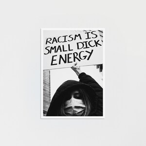 Könnte beinhalten: Ein Schwarz-Weiß-Foto einer Person mit Kapuzenjacke und Gesichtsmaske, die ein rechteckiges Schild über den Kopf hält. Auf dem Schild steht der Text RACISM IS SMALL DICK ENERGY in fetten, schwarzen, handgeschriebenen Großbuchstaben.