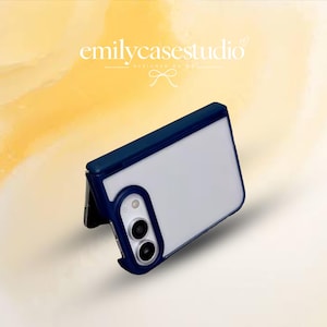 Könnte beinhalten: Eine dunkelblaue, klappbare Smartphone-Hülle mit halbtransparenter Rückseite und verstärktem Kameraausschnitt. Die Hülle ist teilweise geöffnet und zeigt den Klappmechanismus. Der Text emilycasestudio ist oben im Bild zu sehen.