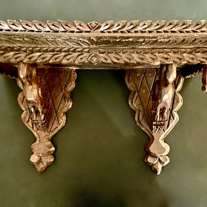 May include: A pair of intricately carved wooden shelf brackets with a decorative top shelf. The brackets feature a diamond pattern and a stylized animal head at the bottom.
