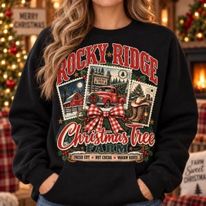 Puede incluir: Una sudadera negra con un estampado gráfico que incluye el texto Rocky Ridge Christmas Tree Farm. El diseño presenta tres ilustraciones estilo sello postal de un camión rojo, un granero y botas vaqueras, acentuadas por un lazo a cuadros rojo y blanco.
