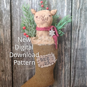 May include: A festive Christmas stocking featuring a stuffed animal head, sprigs of greenery, and red berries. The brown stocking has a patch with "DEC 25". The text "New Digital Download Pattern" is displayed.
