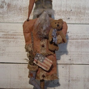 May include: Primitive style handmade Santa doll with a red and white striped stocking, a small teddy bear, and a miniature American flag.