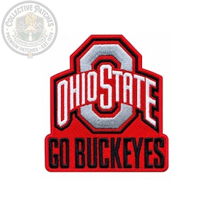 May include: A red, white, and grey embroidered patch featuring the Ohio State University logo with the text OHIO STATE in white letters and the phrase GO BUCKEYES in black letters below, all set against a red background with a black border.