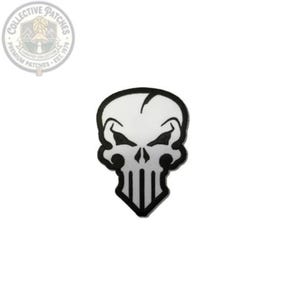 May include: A white embroidered patch featuring a stylised skull design with a black border and black detailing around the eyes, nose and teeth. The skull has a distinct pointed chin and a vertical crack line on the upper forehead area.