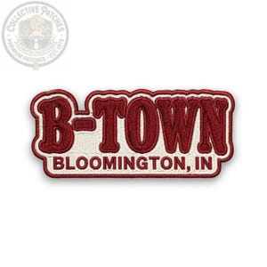 Op de afbeelding: Een rechthoekige geborduurde patch met de tekst B-TOWN in grote, dikke, donkerrode letters met een witte omlijning. Daaronder is de tekst BLOOMINGTON, IN geborduurd in kleinere donkerrode letters op een witte achtergrond met een rode rand.