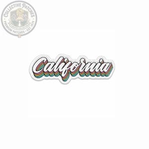 May include: An embroidered patch featuring the word California in a white cursive script with a thick black outline. The lettering is layered with horizontal stripes in shades of red, orange, yellow, green, blue, and purple, creating a rainbow effect.