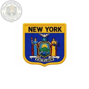 Op de afbeelding: Een schildvormige geborduurde patch met het zegel van de staat New York. Het ontwerp bevat de tekst NEW YORK bovenaan en EXCELSIOR onderaan, met twee figuren naast een centraal landschap met bergen, een zon en een schip.
