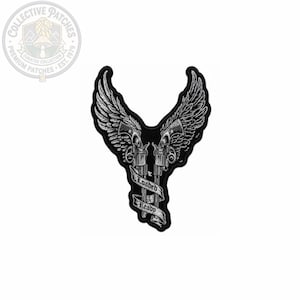 May include: A black and white embroidered patch featuring two revolvers with large feathered wings extending upwards. A banner wrapped around the barrels of the guns displays the text "Loaded" and "Ready" in a stylized black font on a white background.
