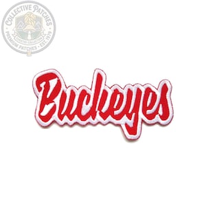 Pode incluir: Um emblema bordado apresentando a palavra Buckeyes em uma fonte cursiva vermelha com uma borda branca. O texto é estilizado com uma aparência espessa e ousada, com um contorno branco que segue as formas das letras para um contraste nítido.
