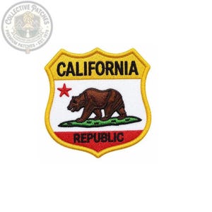 Peut inclure: Un écusson brodé en forme de bouclier avec le texte CALIFORNIA en noir en haut et REPUBLIC en noir en bas. Le centre présente un ours brun marchant sur une parcelle d'herbe verte avec une étoile rouge à gauche sur un fond blanc.