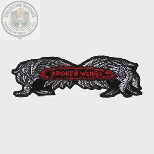 May include: An embroidered patch featuring a pair of stylized black and white wings with a central red banner containing the text BROKEN WINGS in a distressed black font. The design is symmetrical with detailed feather stitching throughout.