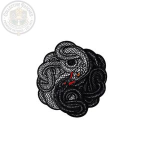 May include: A circular embroidered patch featuring two intertwined snakes in a yin-yang formation. One snake is white with black scale detailing, and the other is solid black. The design includes small red accents for the tongues and orange eyes.