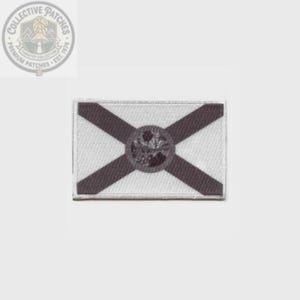 May include: A rectangular embroidered patch featuring the Florida state flag design. The patch has a white background with a dark red saltire cross and a circular seal in the center, displaying a landscape with a palm tree and a sun.