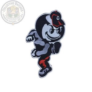 Puede incluir: Un parche bordado que muestra un personaje de dibujos animados en una pose dinámica de carrera. La figura es principalmente negra y gris claro con un acento rojo en la pierna y lleva una gorra de béisbol negra con visera roja. Borde blanco.