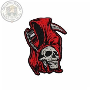 Könnte beinhalten: Ein bestickter Aufnäher mit einem Totenkopf, der einen leuchtend roten Kapuzenumhang trägt. Der Totenkopf ist hellgrau mit schwarzen Schattierungen und Augenhöhlen. Eine silberne Sense mit schwarzem Stiel liegt hinter dem Totenkopf.