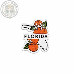 May include: An embroidered patch shaped like the state of Florida with a white outline. The design features two bright orange citrus fruits with green leaves and white blossoms. The word FLORIDA is printed in bold black capital letters.