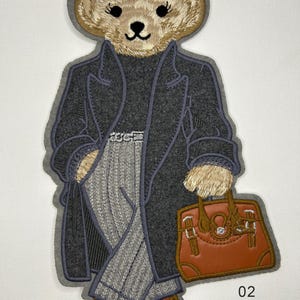 May include: An embroidered patch featuring a teddy bear wearing a dark grey coat, a black turtleneck, and light grey pinstriped trousers. The bear holds a brown handbag and wears brown shoes. Text on the patch reads 02, 9"x5", Sew on.