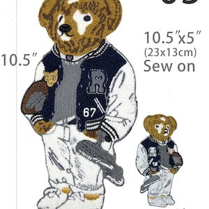May include: A sew-on embroidered patch featuring a brown bear wearing a navy blue and white varsity jacket, a grey sweater, and white pants. The bear holds a brown football and a grey golf club. Dimensions are 10.5 inches by 5 inches. Text reads 05.