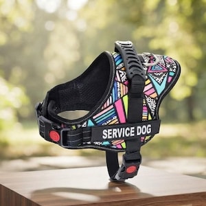 Puede incluir: Un arnés para perro con un patrón geométrico multicolor vibrante y bordes negros. El arnés incluye un asa negra en la parte superior, una anilla en D de metal y un parche negro con el texto blanco SERVICE DOG. Tiene correas negras ajustables.