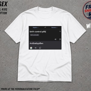 May include: A white short-sleeved t-shirt featuring a graphic print of a digital translation interface. The graphic displays the English text birth control pills being translated into the German word Antibabypillen with a search bar and icons.