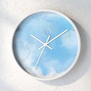 May include: A round wall clock with a white frame and a face featuring a light blue sky with soft white clouds. The clock has three thin white hands positioned at the center, indicating the time against the printed sky background.