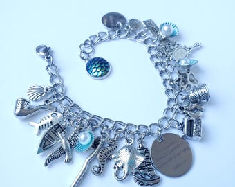 May include: Silver charm bracelet featuring various nautical-themed charms, including a seahorse, stingray, boat, and fish. The bracelet also includes a charm with the quote "The seaweed is always greener in somebody else's lake."