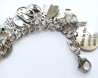 May include: Silver charm bracelet featuring various charms, including a clock, key, and owl. One charm has the text "Who in the world am I?" The bracelet has a lobster clasp closure.