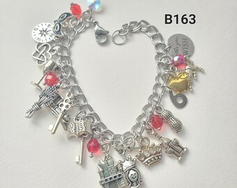 May include: Silver charm bracelet with various charms, including a crown, castle, keys, and a wheat bundle. The bracelet also features red and iridescent beads, and a small heart charm. The text "wish you" is on a round charm.