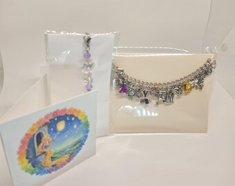 May include: A silver charm bracelet featuring various small pendants, a beaded charm with a lobster clasp, and a folded card displaying a colorful illustration of a character with long hair reaching toward a floating lantern in the night sky.