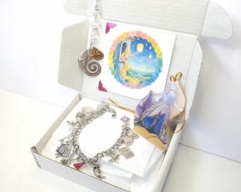 May include: An open white box containing a charm bracelet, a print of a princess, a charm with a chameleon design, and other decorative items. The bracelet is silver with various charms. The print depicts a princess with long hair.
