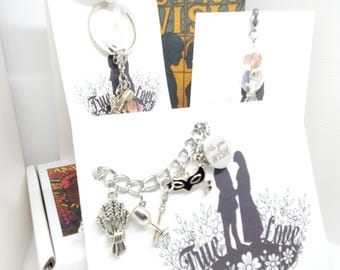 May include: A silver-toned charm bracelet featuring a black mask, a goblet, a wheat sheaf, and a round white charm with the text As You Wish. The bracelet is displayed on a white card with a black silhouette of two figures and the text True Love.