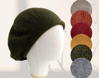 May include: An olive green knit beret displayed on a mannequin head. Beside the beret are color swatches in shades of gray, orange, red, yellow, green, and blue. The beret is a classic style, suitable for various outfits.