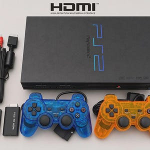 以下が含まれることがあります： 青いロゴが付いた黒いPlayStation 2本体、青とオレンジの半透明コントローラー2台、8MBメモリーカード、黒いPS2-HDMI変換アダプター、黒いAVケーブル。HDMIおよびHigh-Definition Multimedia Interfaceというテキストが表示されています。