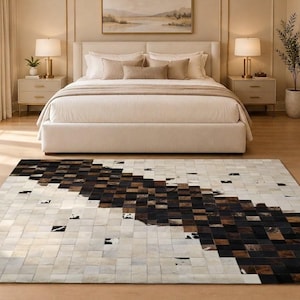 May include: A rectangular area rug featuring a patchwork design of small square tiles in shades of white, cream, brown, and black. The pattern displays a diagonal gradient transition from light tones to dark tones across the surface.