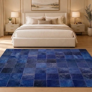 May include: A rectangular area rug featuring a patchwork design of square tiles in various shades of deep blue. The rug is composed of individual leather-like squares stitched together, creating a textured surface with tonal color variations.