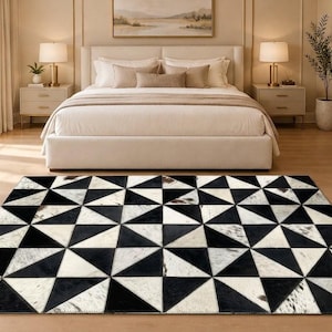 May include: A rectangular area rug featuring a geometric pattern of alternating black and white triangular patches. The rug is constructed from individual pieces of cowhide, showcasing a mix of solid black and mottled white textures.