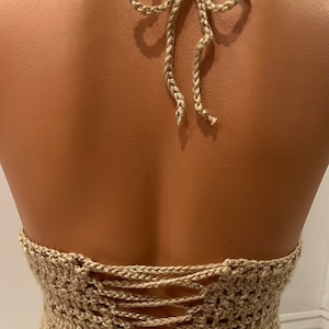 May include: A beige crochet halter top with a lace-up back.