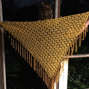 Pu&ograve; includere: Uno scialle in crochet giallo senape con un delicato motivo floreale e bordi a frangia.