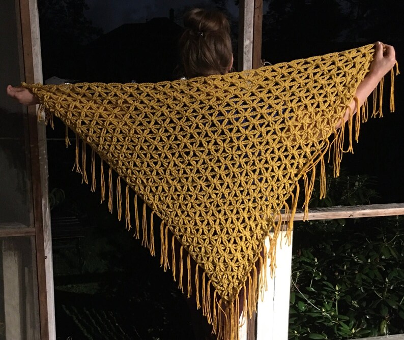 Pu&ograve; includere: Uno scialle in crochet giallo senape con un delicato motivo floreale e bordi a frangia.