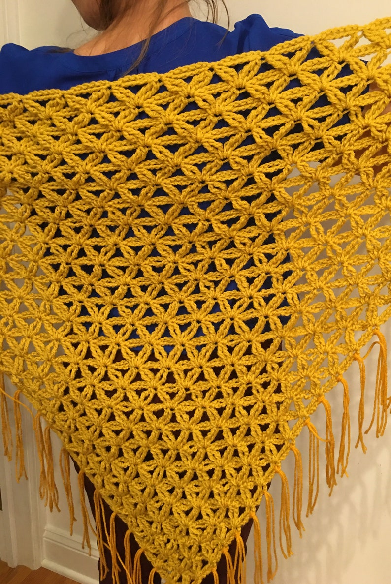 Pu&ograve; includere: Uno scialle all'uncinetto giallo senape con frange. Lo scialle &egrave; realizzato con un punto delicato che crea un motivo floreale.
