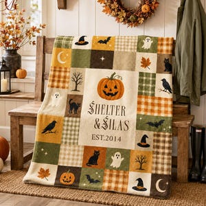 May include: A rectangular throw blanket featuring a patchwork design with Halloween motifs including pumpkins, black cats, ghosts, bats, moons, and witch hats. The center panel displays the text "SHELTER & SILAS" and "EST. 2014" in black.