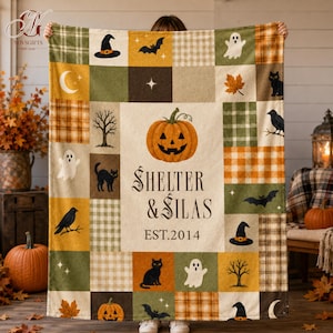 Op de afbeelding: Een rechthoekige plaid met een patchworkontwerp van Halloween-thema vierkanten in oranje, groen en crème. Het middenpaneel toont een pompoen, de tekst "SHELTER & SILAS" en "EST.2014", omringd door geesten, katten en vleermuizen.