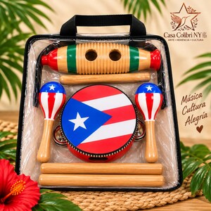 May include: A musical instrument set in a clear carrying case featuring a wooden guiro with green and red ends, two maracas painted with the Puerto Rican flag, and a round tambourine with the same flag design, plus three wooden sticks.