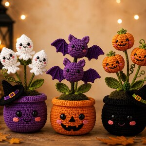 May include: Three crocheted Halloween-themed potted plants. The left pot is purple with three white ghosts. The center pot is orange with two purple bats. The right pot is black with three orange pumpkins. Each pot features a smiling face.